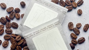 Drip coffee paper bags with coffee beans on a grey concrete background