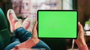 Feminine Hand Horizontally Holding a Tablet with Green Screen Display. Female is Relaxing on a Couch Stock Image - Image of mockup, livingroom: 291595069