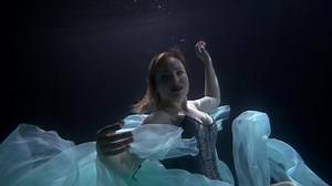 beautiful mermaid with big boobs is swimming underwater, subaquatic shot in sea or ocean