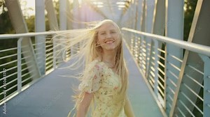 Woman looking back on bridge. Pretty blonde woman looking back at camera while running on bridge with wavy hair. 4k