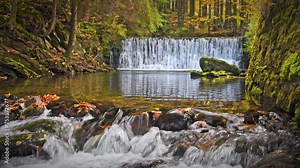 Mountain river with a cascade, cold water flows through the riverbed between wet rocks. Autumn mountain landscape.