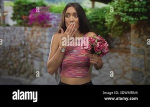 Woman taking photo of pink peonies with smartphone.