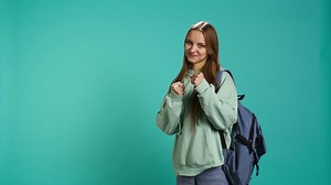 Woman doing fighting stance, pretending to do boxing, isolated over studio background. Young fighter throwing punches, doing athletic guard pose during combat practice, camera B