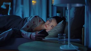 Woman Lying in Bed Using Smartphone at Night