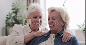 Mature lesbian couple at home on sofa