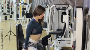 Female doing weight exercise for legs by Inner Thigh Machine in the sports gym, bodybuilder concept. Girl doing exercise for legs on a press machine in the gym.