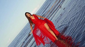 Young woman in long red dress with lacy skirt and slit
