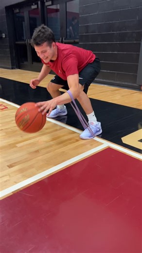 🔥 This drill is all about leveling up your off-hand handle using tension, technique, and high reps. Start in a low stance, loop the resistance band under your foot and around your off-hand wrist or forearm, then go to work. Pound the ball hard and fast using only your off-hand while keeping your eyes up 👀. Focus on dribbling with your finger pads (not your palm) for better feel, precision, and ball control 🏀. That fingertip touch builds elite-level awareness and confidence when you’re pressur
