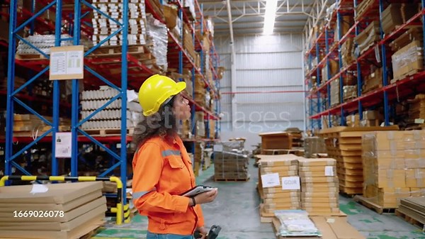 female warehouse worker uses a tablet while inspecting merchandise...