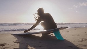 clip-3469420467-woman-surfer-knelt-down-by-surfboard-waxing