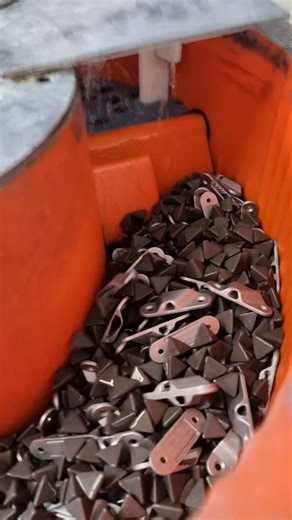 This is a tumbling machine! It's filled with a special stone-like media which vibrate and tumble against our cleats. This knocks off any protruding burrs that may be left from casting, smoothing the surface. Once finished the machine runs in reverse, sending the cleats and media to be separated - the stones fall through the filter gaps and the cleats run off the machine, ready for the next stage of the process! #howitsmade #factory #injectionmolding | Clamcleats Limited | Facebook