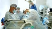 Surgeon, wearing medical mask and special loupes, performs surgery...