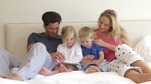 clip-2873164-children-sitting-between-parents-bed-reading-book
