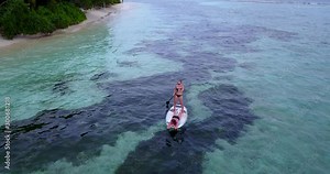 Two young ladies enjoying their sailing around tropical island bay by a surfboard, watching corals and algae of Cook islands