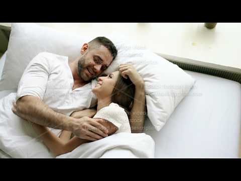 Young beautiful and loving couple talk and hug into bed while waking up in the morning. Top view of