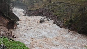 Water floods and landslide during heavy rain. Swollen river in autumn. Muddy and dirty water flows. Raging river.