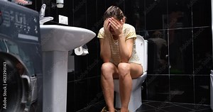 Woman suffers from diarrhea and is sitting on toilet