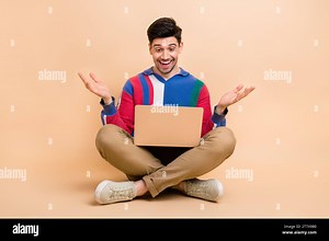 Full body length photo of funny positive guy talking at video call conference using laptop at home isolated on beige color background Stock Photo - Alamy