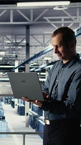 Vertical Data center IT professional deploys deep learning software on infrastructure racks. Server farm engineer trains AI systems with datasets using laptop to support applications, camera A