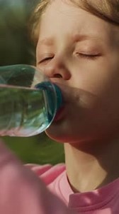 Child Drinks Water From Bottle Outdoors