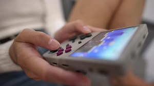 Close-up in shallow depth of field. Unrecognizable portable retro console in hands of young Caucasian woman. Girl plays retro games holding retro device for emulating old console games