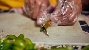 A women chopping green chilies into pieces for pickle / achar preparation.