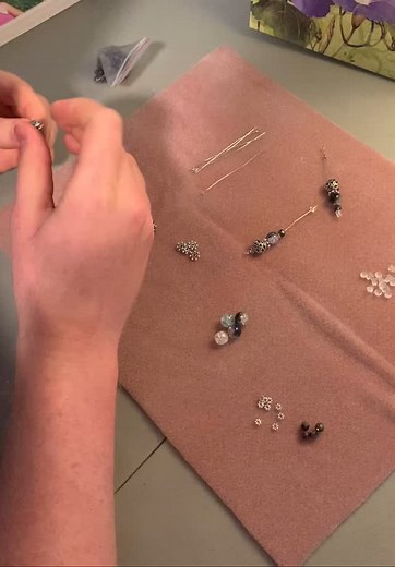 Mr. Puzzle is making another batch of zipper pulls. Just look at the tiny beads he can manage—he’s got such steady hands and sharp eyes! I’m always amazed by his speed in assembling the pins. #crossstitchersofinstagram #zipperpulls #projectbagsforcrossstitchers #xstitchersofinstagram #beadedaccessories #disabilityawareness | Starry Village Stitcher