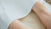 Masseuse removes white sheet from young woman before massage therapy...