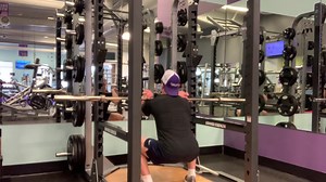 This is the 9th phase of the squat pyramid. The primary movers for this movement are the quad and glute muscles. For this exercise you will need a barbell and a squat rack. To begin you will have to set up the squat rack so that the bar is at about chest height. Put an appropriate amount of weight on the bar. Step underneath the bar so that it is resting on your shoulders, slightly above your clavicle. Place your hands about a thumb distance away from the outside of your shoulders with your palm
