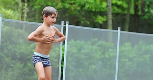 Child teasing people inside swimming pool Young boy sticking tongue out and then enters water in 4K
