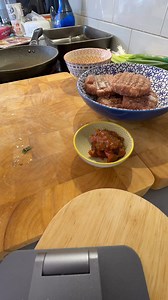 I’m making something I’ve called taco pockets. I’m using ingredients I have in the fridge such as leftover burger patties and little soy sauce packets from the local sushi shop I’ve held onto. I mash the mince up and as spring onion heads soy sauce and some of my chilli jam and stir it all up. I get the oven tray lay down some baking paper and spread melted butter then add some greater chews and then a spoon full of the mix then cut four squares of puff pastry to cover and was with a little butt