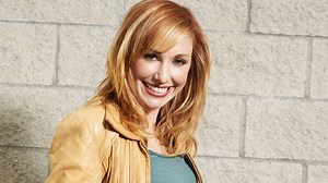 Kari Byron smiling in front of a brick wall Rare Gallery wallpaper