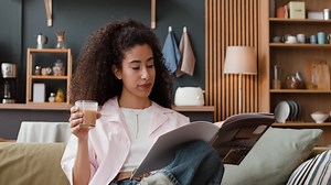 Woman Reading a Magazine and Enjoying a Drink on a Couch at Home | Free Stock Video Footage