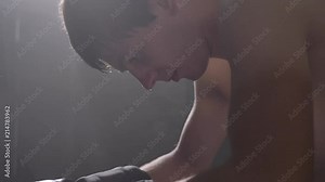 Profile of sweaty shirtless boxer sitting and getting up, going to fight, drop of water on his face