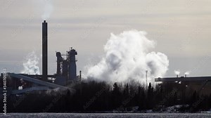 Much white steam emission from paper production factory, ecologically clean, no toxic smoke, just hot water steam. Umea river coast, Obbola locality, close to Umea, Vasterbotten county, Sunny spring