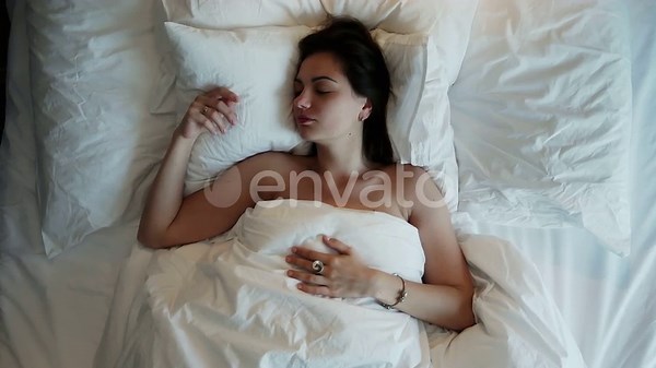 Top View of Beautiful Young Woman Waking Up and Stretching in the Early Morning, Lying in Bed