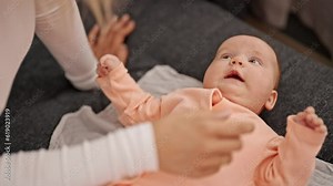 Mother and daughter lying on sofa massaging baby at home