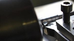 Close-up lathe machine operation by cutting the metal tube. vintage lathe machine tool operates with metal detail under mature worker control in old production plant workshop. Slow motion