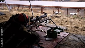 aiming and shooting with a rifle at a target from a prone position