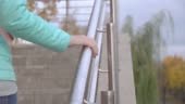 young woman climbs stairs and takes up the metal railing.
