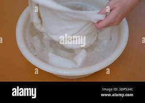 Female hands carefully washing white clothes in a plastic basin filled with clear water, showcasing traditional hand laundering methods and domestic chores for cleaning and hygiene Stock Video Footage - Alamy