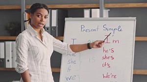 A talented African American woman teaches English grammar concepts online. She engages students with interactive lessons on present simple, showcasing her teaching skills.