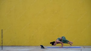 Positive young woman having first remote yoga lesson trying to make perfect pose laughing at small failures on practicing, female bewbie in training doing asanas enjoying active lifestyle and vitality