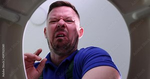 Unhappy man plumber opening lid of toilet and closing nose because of unpleasant smell bottom view 4k movie. Removing blockages in sewerage concept