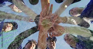 Ground cam capturing eight athletes in baseball caps pregame huddling and stacking hands for unity