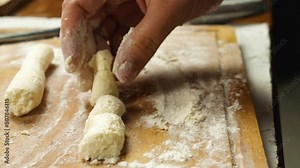 A close-up of a woman's hand sprinkles flour on the kitchen board and forms a dumpling of cottage cheese dough. A traditional dish of Russian and Ukrainian cuisine