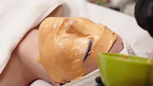 A young woman receives a revitalizing alginate face mask from a skilled cosmetologist in a sleek, modern beauty clinic. Perfect for promoting premium skincare treatments in your ads