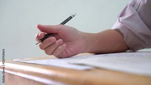 Exam classroom of students group hands holding fill in carbon paper sheet or test papers on wood desk, School testing PISA or exercise computer sheet in college or university in Asian, Thailand. 4K