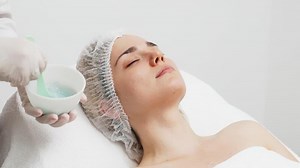 A cosmetologist applies an alginate face mask on a young woman in a modern salon. This treatment boosts skin hydration and rejuvenation, perfect for highlighting premium skincare in your ads