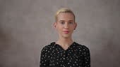 Elegante Transfrau zieht rosa Perücke auf beige Hintergrund